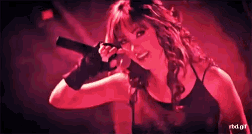 a woman is singing into a microphone with a rbd.gif written below her