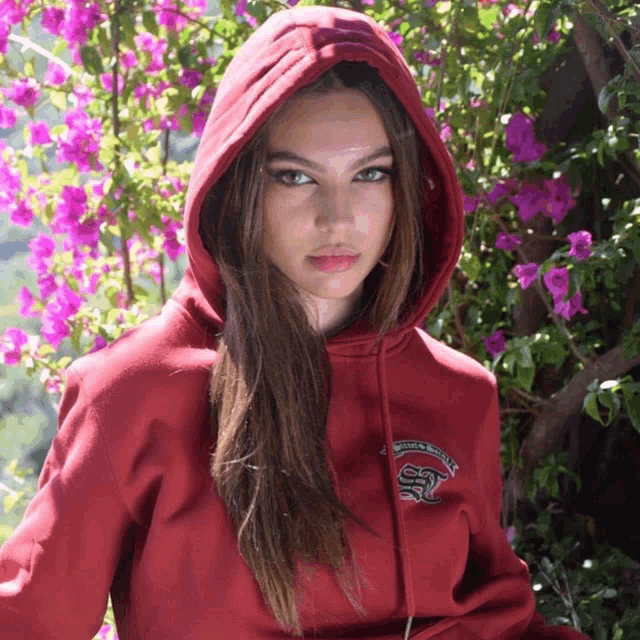 a woman wearing a red hoodie with a snake embroidered on the front