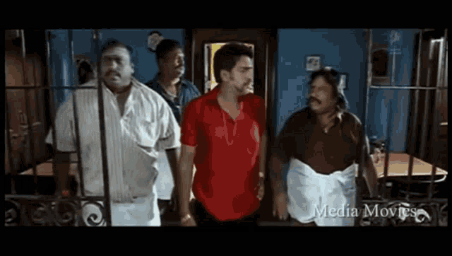 a group of men are standing in a room with the words media movies on the bottom right