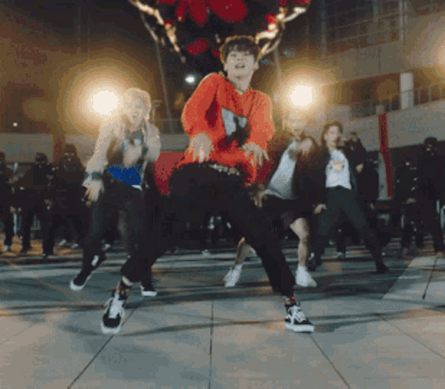 a group of people are dancing on a street at night