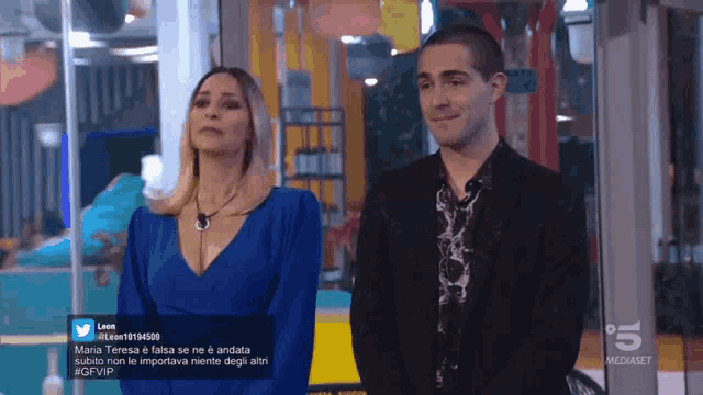 a woman in a blue dress is standing next to a man in a suit