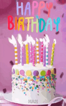 a birthday cake with candles and sprinkles on it is on a plate on a table .