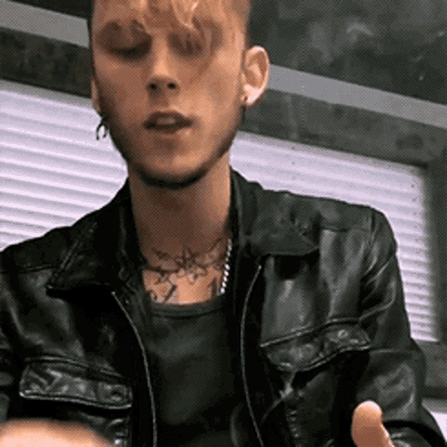 a man in a black leather jacket has a tattoo on his neck