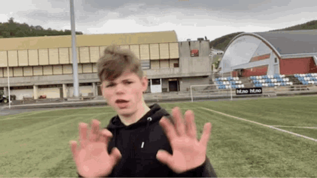 a young man is standing on a soccer field with his hands up in front of a building that says mino