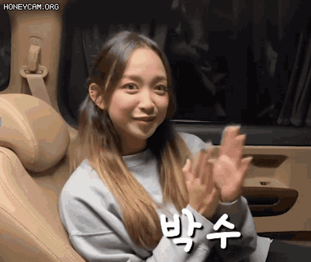 a woman is sitting in the back seat of a car and clapping her hands .