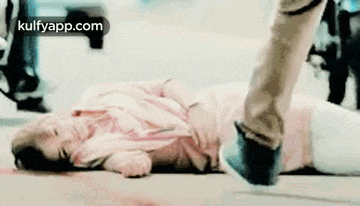 a woman is laying on the ground with a man 's foot on her .