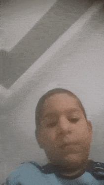 a young boy in a blue shirt is making a funny face while looking at the camera .