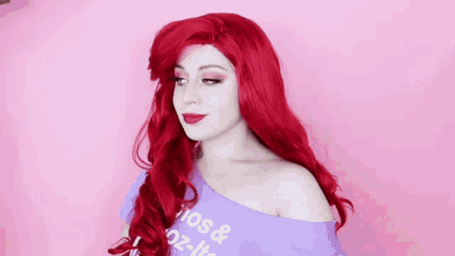 a woman with red hair is wearing a wig and a purple shirt .