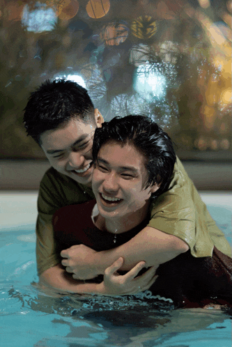 two men are hugging each other in a pool and they are laughing