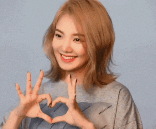 a woman in a balenciaga shirt makes a heart with her hands