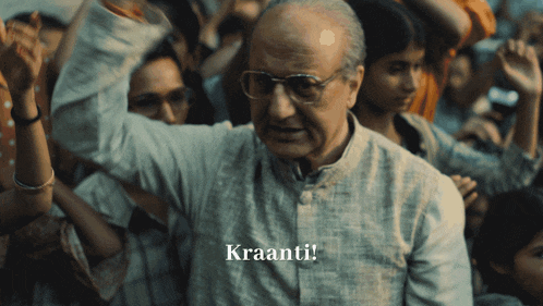 a man with glasses stands in front of a crowd and the word kraanti is above him