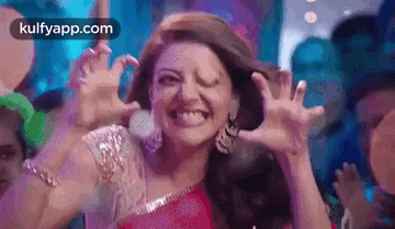 a woman in a pink dress is making a funny face while dancing in a club .