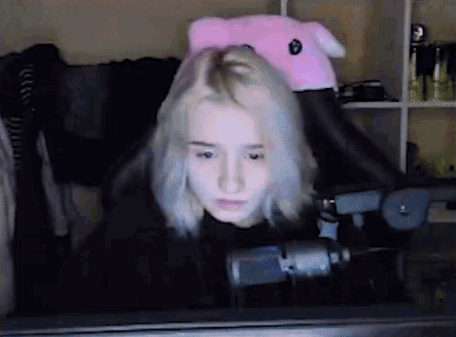 a girl with blonde hair is wearing a pink hat