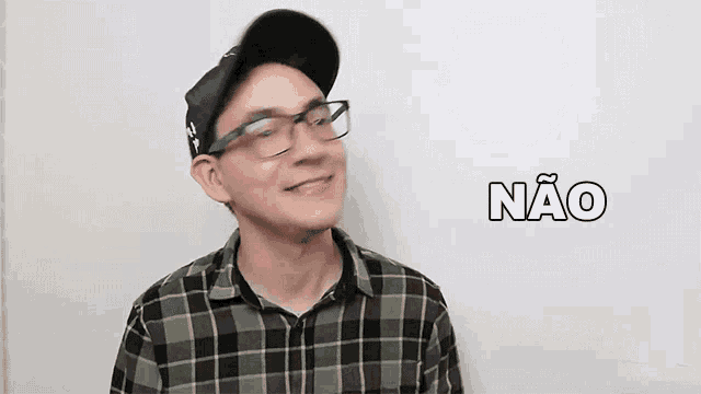 a man wearing glasses , a hat and a plaid shirt is making a funny face .