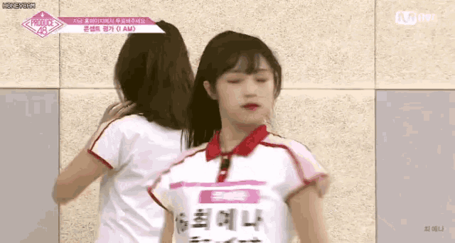 two girls are hugging each other while standing next to each other .