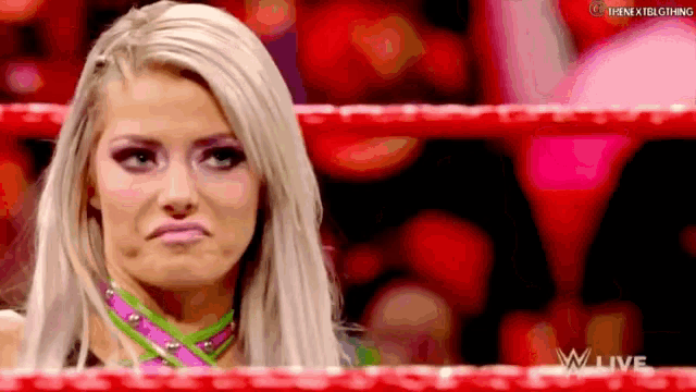a female wrestler is making a funny face in a wrestling ring .