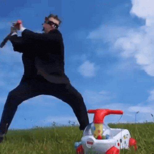 a man in a suit is playing with a fisher price toy car