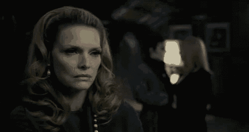 a woman is standing in a dark room with a man and a woman standing behind her .
