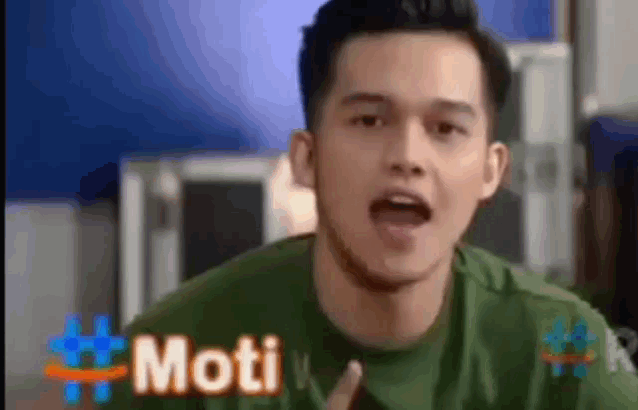a man in a green shirt is making a funny face and the word moti is in the corner