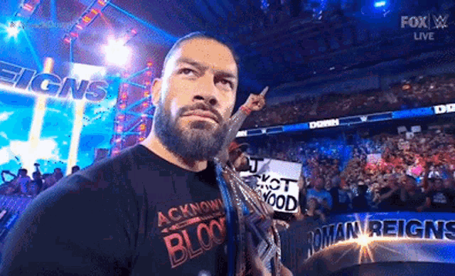a man with a beard is standing in front of a crowd in a stadium holding a trophy .