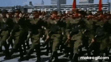 a large group of soldiers marching down a street in a parade .