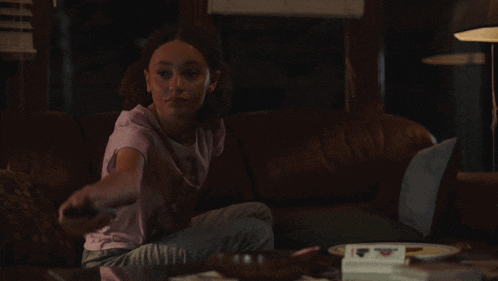 a girl sitting on a couch playing a game with a remote control
