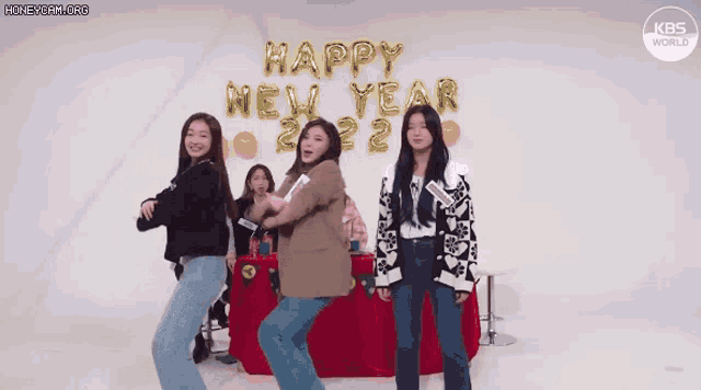 a group of women are dancing in front of a sign that says happy new year .