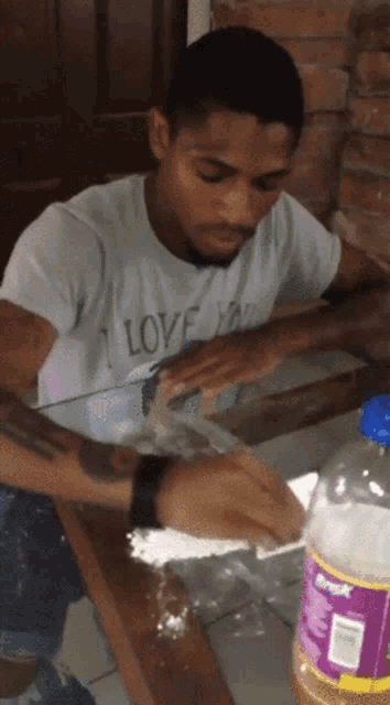 a man wearing a white shirt that says " i love you " sits at a table