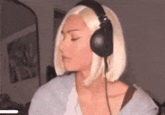 a woman wearing headphones and a wig is sitting in a room .