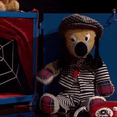a stuffed animal sitting next to a red telephone