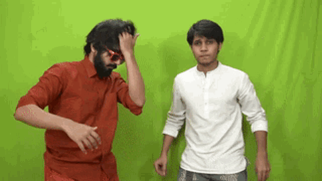 two men are dancing in front of a green screen .