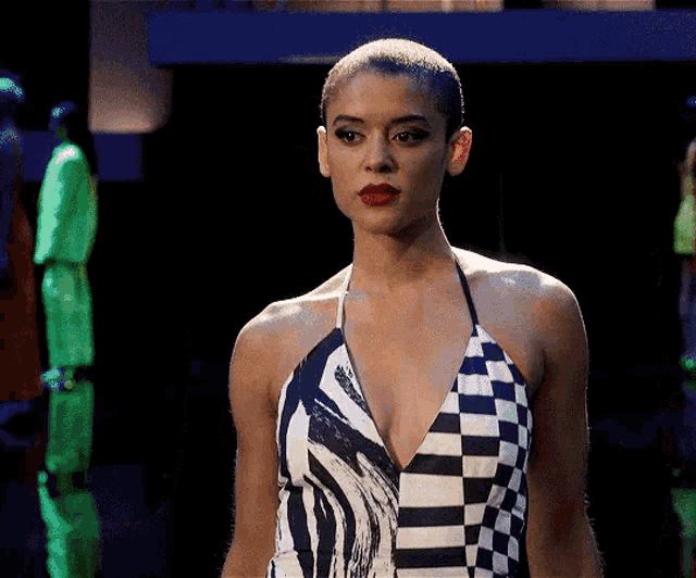a woman with a shaved head is wearing a black and white checkered dress .