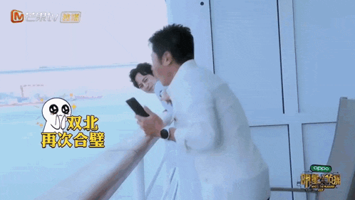 a man standing on a balcony holding a cell phone with the word oppo on the bottom