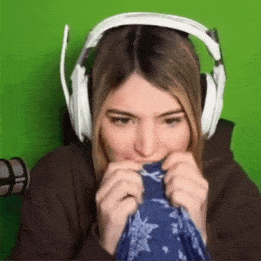 a woman wearing headphones is covering her mouth with a piece of cloth .