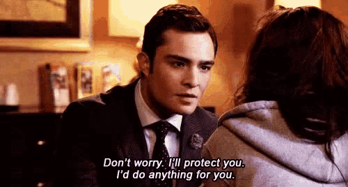 a man in a suit and tie is talking to a woman who is wearing a sweatshirt .