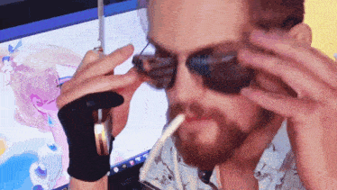 a man wearing sunglasses is smoking a cigarette in front of a computer screen
