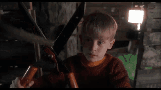 a young boy is holding a pair of scissors in his hand