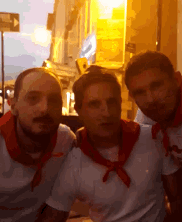 three men are posing for a picture with one wearing a red scarf