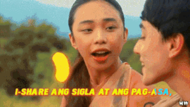 a man and a woman are standing next to each other with the words i-share ang sigla at ang pag-asa above them .