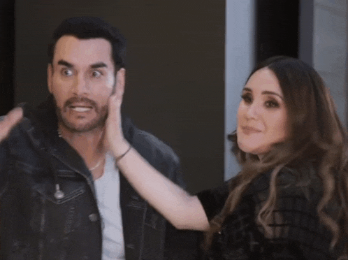 a woman is touching a man 's face and making a funny face