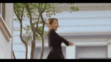 a woman in a black dress is walking down a sidewalk .