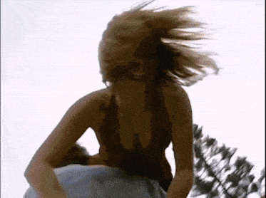 a woman with her hair blowing in the wind in a bikini top