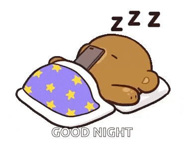 a cartoon teddy bear is sleeping in a bed with a cell phone on his head .