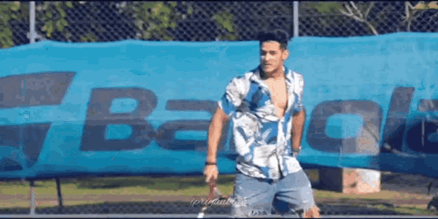 a man is playing tennis in front of a babolat sign