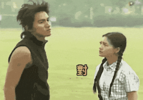 a man and a woman are standing next to each other in a field with chinese characters on the ground