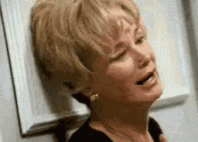 a woman is leaning against a wall with her eyes closed and crying .