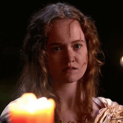 a woman with a scar on her face is holding a candle .