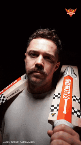 a man with a mustache is holding a cricket bat that says gray nicolls