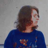 a woman wearing a blue sweater with flowers on it looks to the side