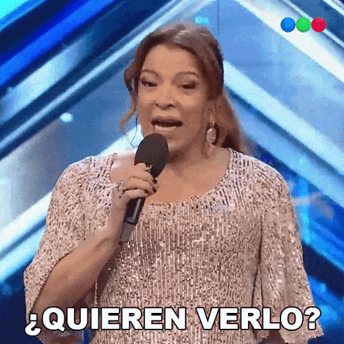 a woman in a sequined dress is singing into a microphone and says quieren verlo